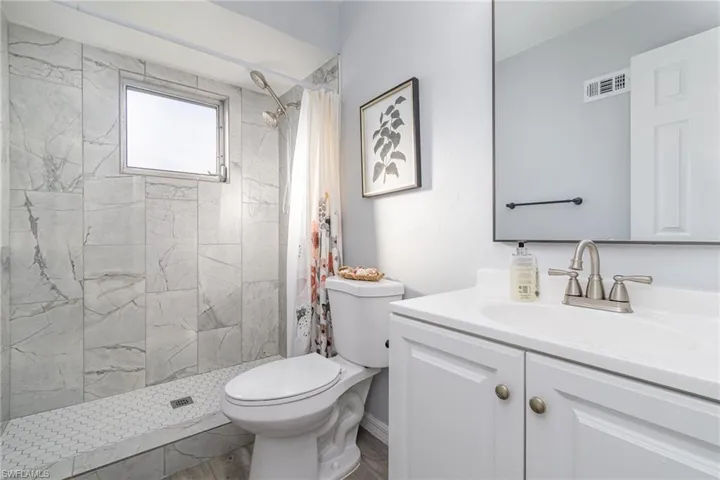 Bathroom featuring vanity, curtained shower, and toilet