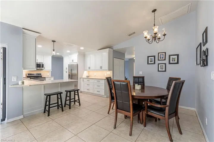 Dining room featuring light tile patterned floors, lofted ceiling, a chandelier, and recessed lighting
