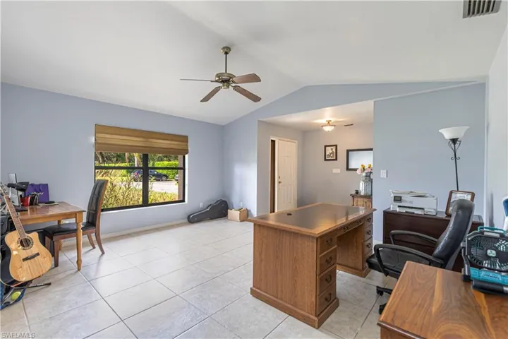 Office area featuring light tile patterned flooring, ceiling fan, and lofted ceiling