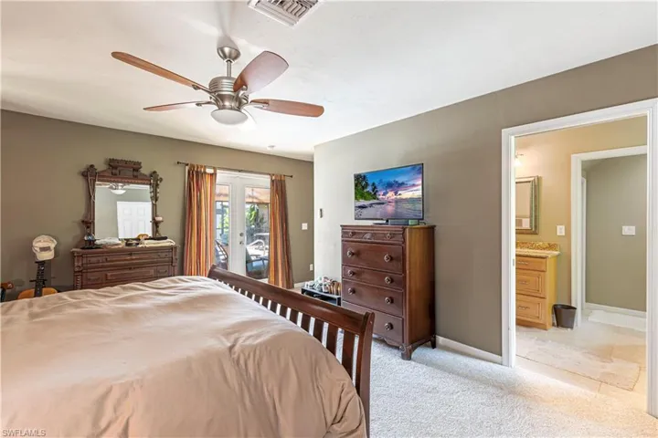 Bedroom with access to outside, light colored carpet, a ceiling fan, and ensuite bath