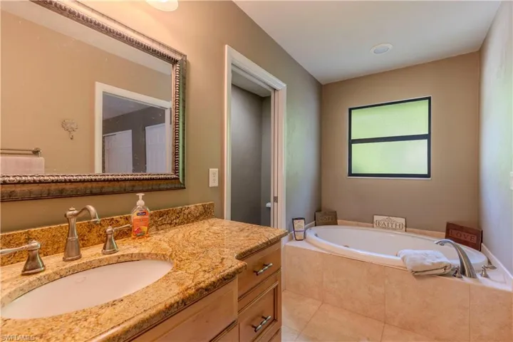 Bathroom featuring vanity, a garden tub, and tile patterned floors