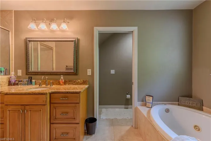 Bathroom featuring vanity, a tub with jets, and tile patterned flooring