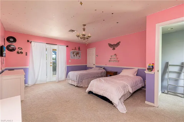 Carpeted bedroom featuring access to outside and a chandelier