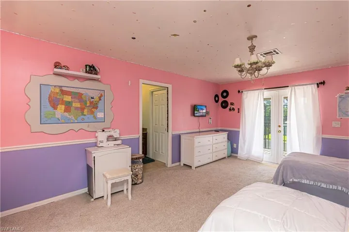 Bedroom with access to outside, light carpet, a chandelier, and french doors