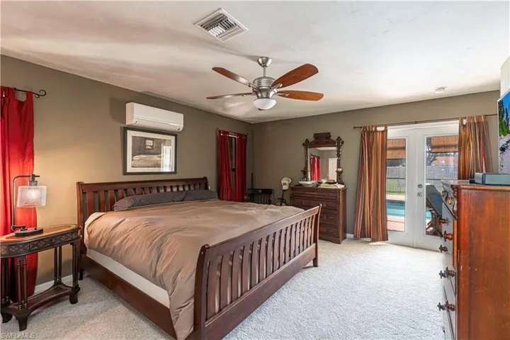 Bedroom featuring access to exterior, french doors, light carpet, a wall mounted AC, and ceiling fan