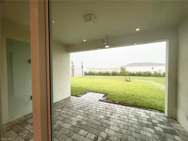 Covered patio featuring paver flooring, recessed lighting, and a ceiling fan, opening to a grass lawn