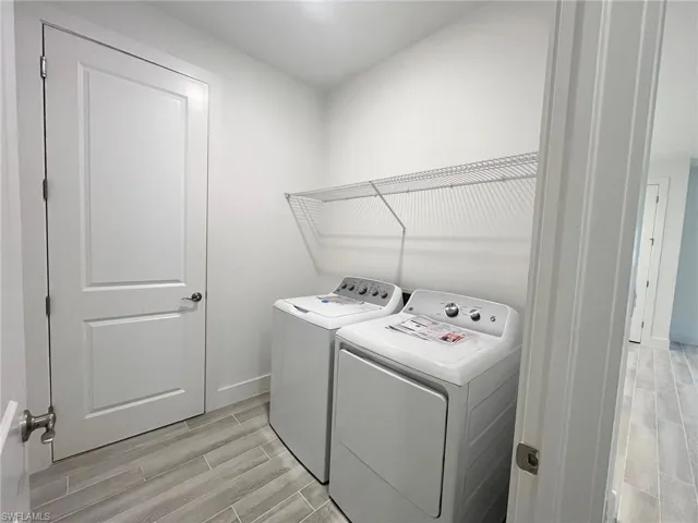 Laundry room featuring wood-finish tile flooring, white-panel interior door, and wall-mounted wire shelving