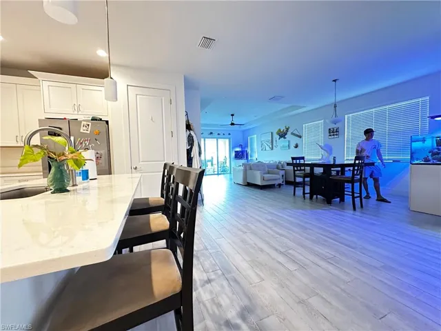 Kitchen featuring a stone-surface island with an integrated sink and wood-finish flooring extending throughout the main area