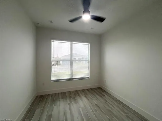 Neutral-toned interior space featuring wood-finish flooring, a multi-blade ceiling fan with an integrated light fixture, recessed lighting, and a window with horizontal blinds