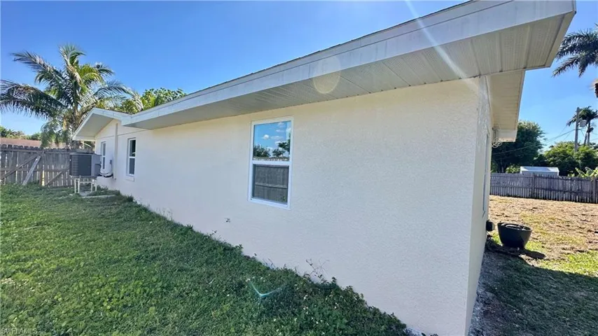 View of property exterior featuring cooling unit, stucco siding, fence, and a yard
