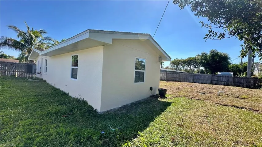 View of property exterior featuring stucco siding, fence, and a lawn