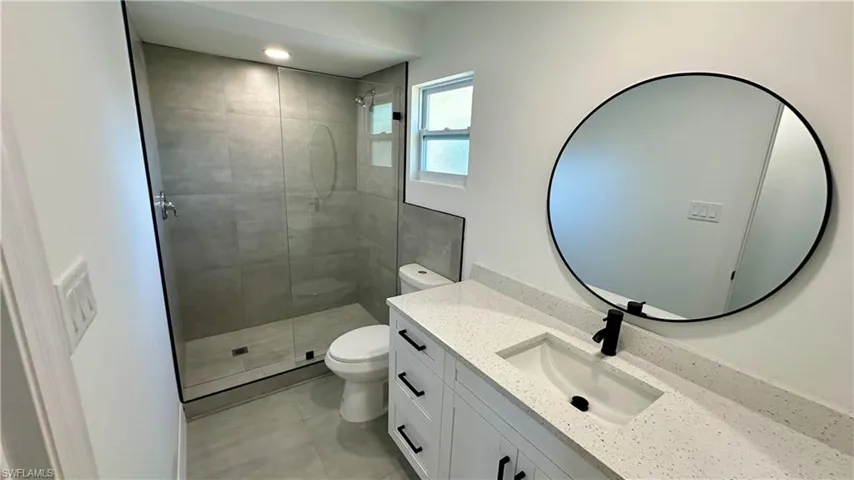 Bathroom featuring a shower stall, toilet, tile patterned flooring, and vanity