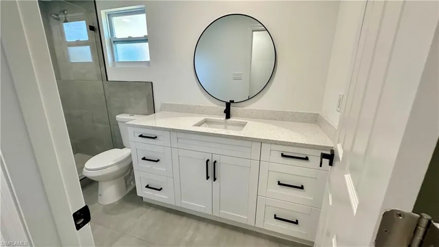 Full bath featuring tile patterned floors, a tile shower, toilet, and vanity