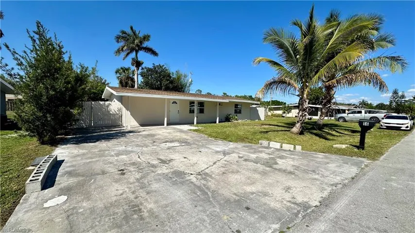 Ranch-style house with a front lawn, driveway, an attached carport, and fence