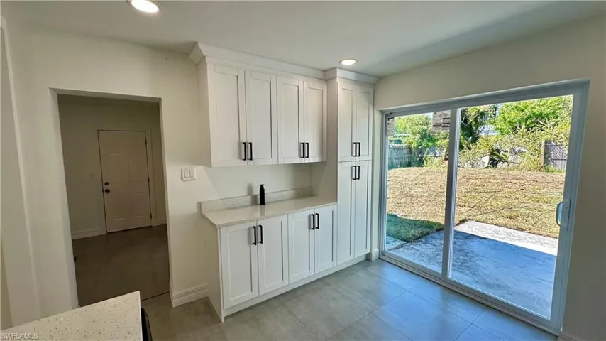 Kitchen featuring white cabinets, light stone counters, baseboards, and recessed lighting