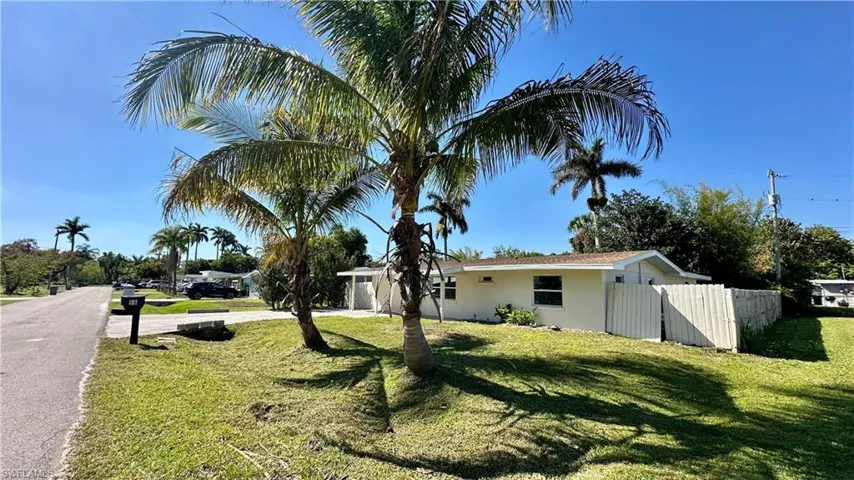 View of side of property with driveway, a yard, fence, and stucco siding