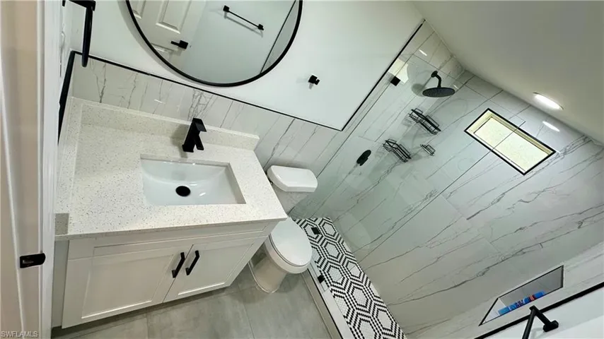 Bathroom with toilet, tiled shower, and vanity
