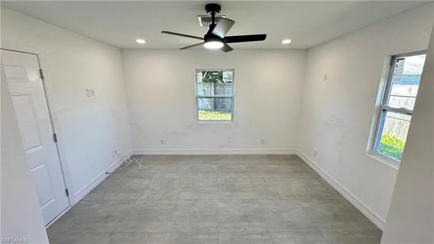 Unfurnished room featuring a wealth of natural light, baseboards, and a ceiling fan