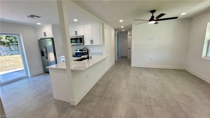 Kitchen with a sink, white cabinetry, appliances with stainless steel finishes, visible vents, and ceiling fan