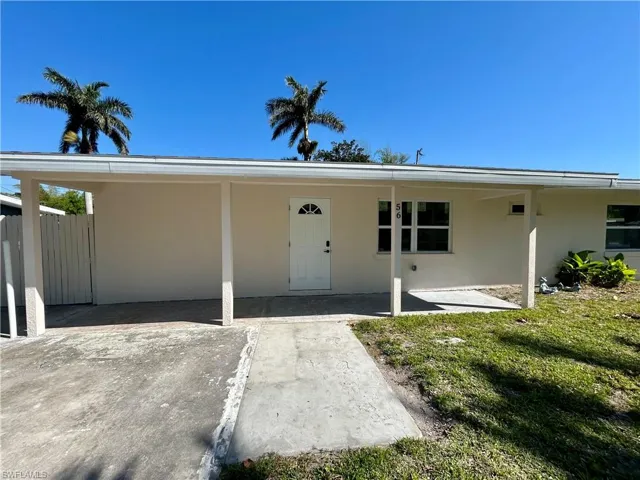 Property entrance featuring fence, stucco siding, and a yard