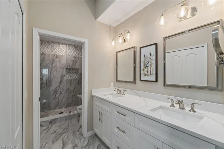 Primary renovated ensuite bathroom featuring double vanity, marble floors and closet.