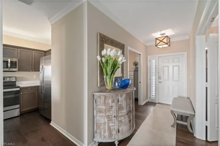 Foyer featuring custom lighting, crown molding and wood floors, access to the 3rd bedroom and the kitchen.