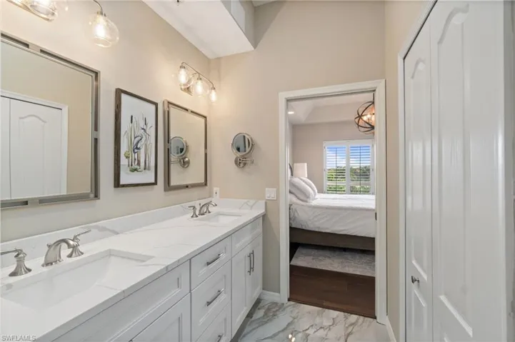 Primary renovated ensuite bathroom featuring double vanity, marble floors and closet.