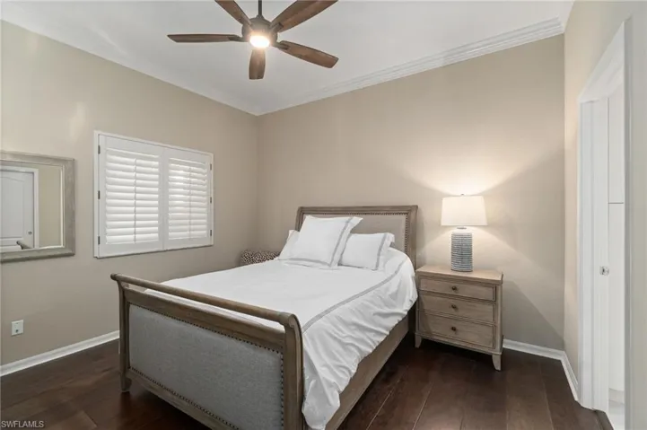 Guest bedroom featuring crown molding, wood flooring and ceiling fan.