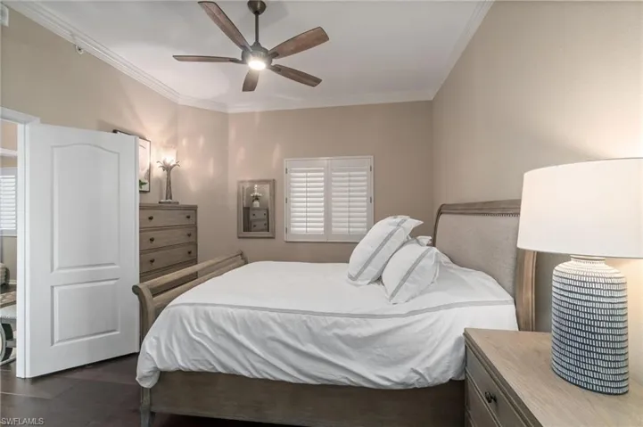 Guest bedroom featuring crown molding, wood flooring and ceiling fan.