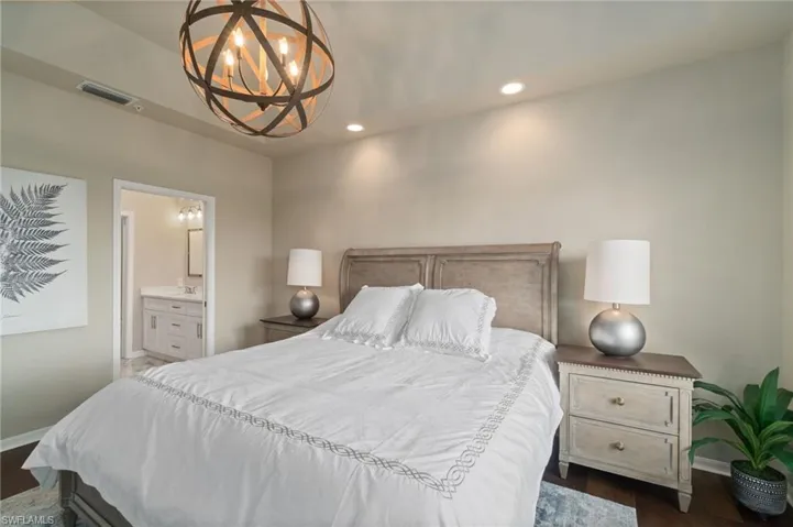 Primary bedroom with custom lights, en-suite primary bathroom and wood flooring.