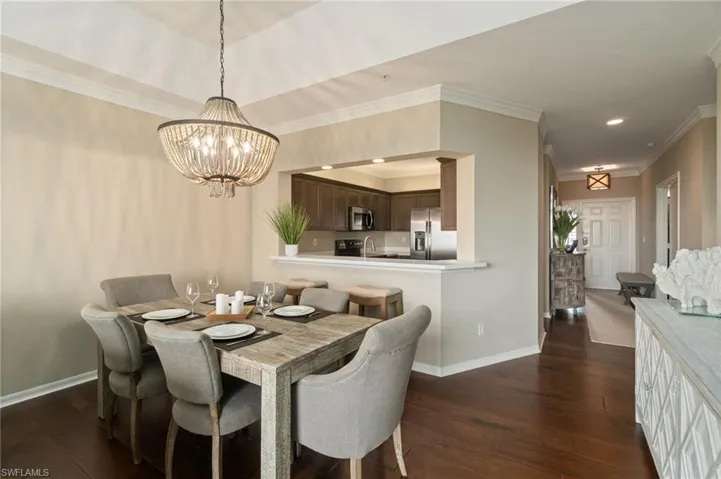 Great room with dining area, vaulted ceiling, wood floors, custom lighting and crown molding facing the kitchen.