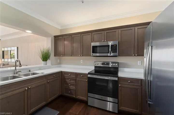 Kitchen with wood cabinetry, stainless steel appliances, wood flooring and recessed lighting.