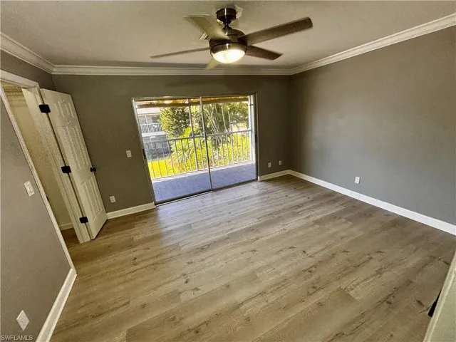 Empty room with ceiling fan, light wood-type flooring, and crown molding