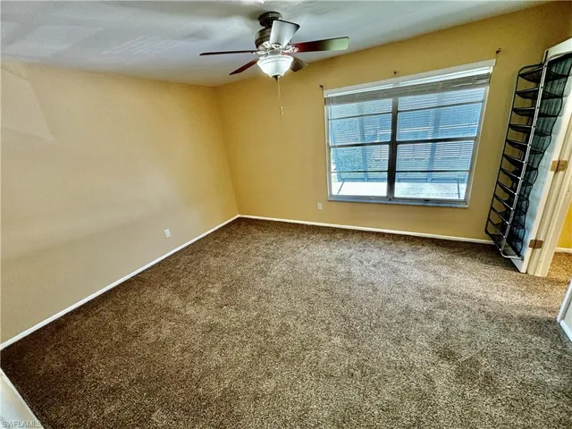 Empty room featuring ceiling fan and carpet floors