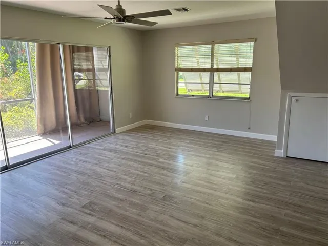 Empty room with a healthy amount of sunlight, wood-type flooring, and ceiling fan