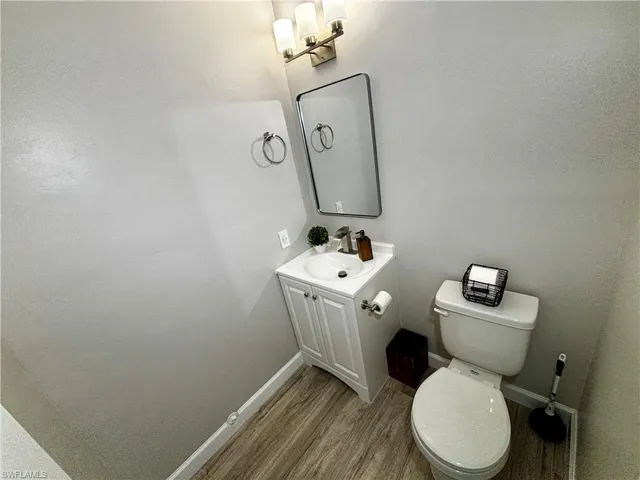 Bathroom featuring wood-type flooring, vanity, and toilet