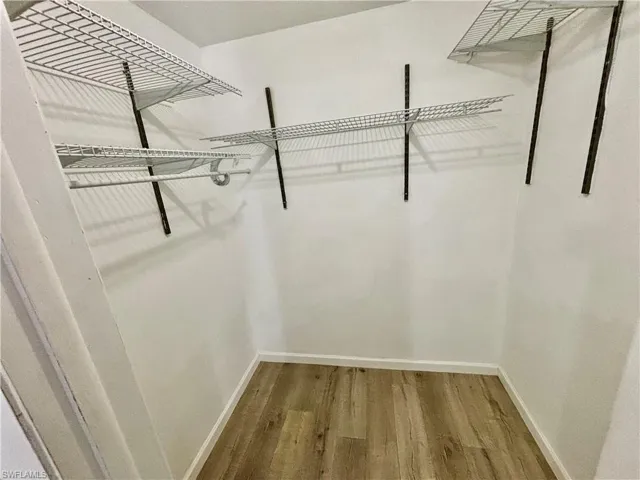 Walk in closet with hardwood / wood-style floors