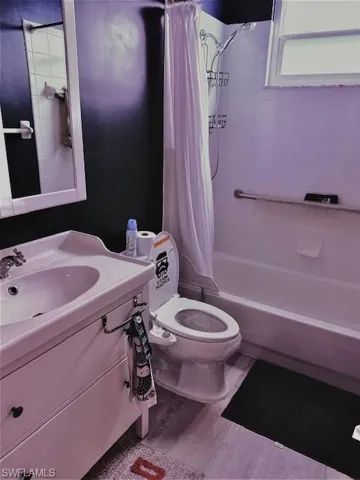 Full bathroom featuring wood-type flooring, toilet, shower / bathtub combination with curtain, and sink