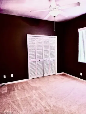 Unfurnished bedroom featuring carpet flooring, ceiling fan, and a closet