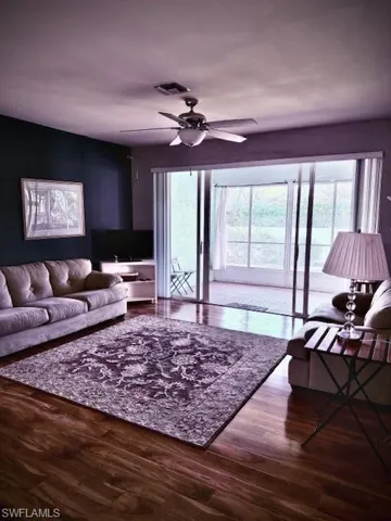 Living room with hardwood / wood-style floors, ceiling fan, and a healthy amount of sunlight