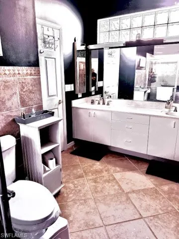 Bathroom with tile patterned floors, vanity, tile walls, and toilet