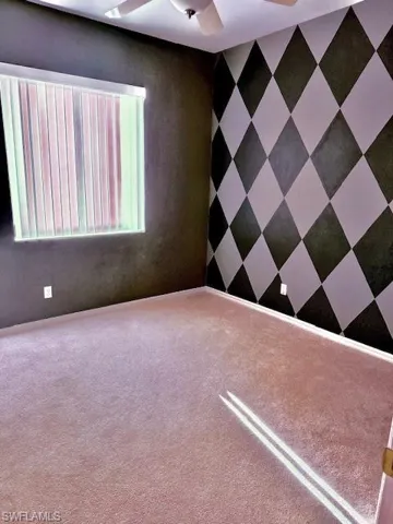 Unfurnished room featuring ceiling fan and carpet
