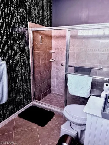 Bathroom featuring tile patterned flooring, toilet, and an enclosed shower