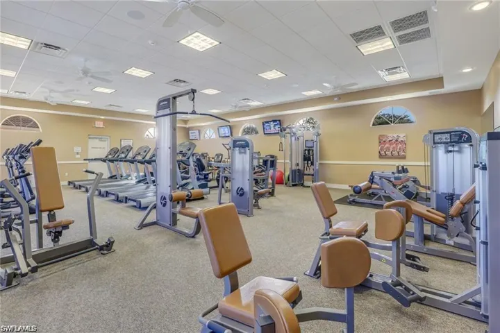 Gym with ceiling fan, carpet floors, and a drop ceiling