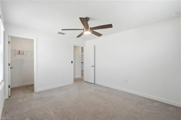 Second Floor- Spacious room with light gray carpet, white walls, and a ceiling fan with wood-finish blades