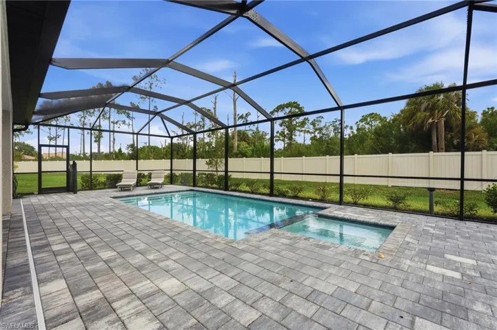Screened outdoor living area featuring a rectangular pool and integrated spa