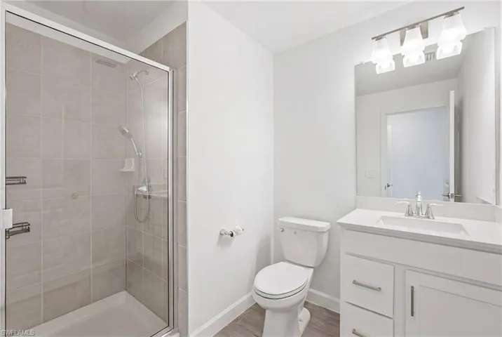 Second Floor- White bathroom featuring a glass-enclosed shower with light gray tile surround, a single vanity with a white countertop and integrated sink, a large wall-mounted mirror, and a three-light vanity fixture