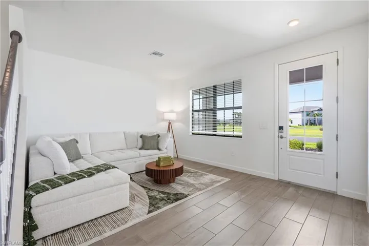 Bright living area with wood-finish flooring and a white paneled door with glass inserts