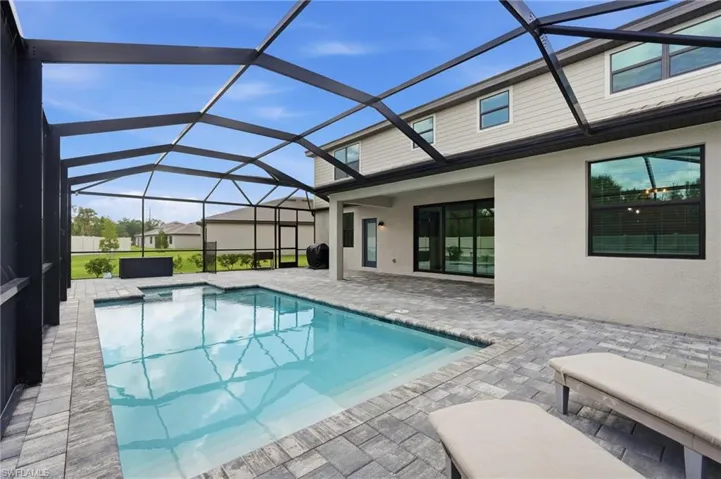 Screen-enclosed swimming pool with integrated spa and paver decking