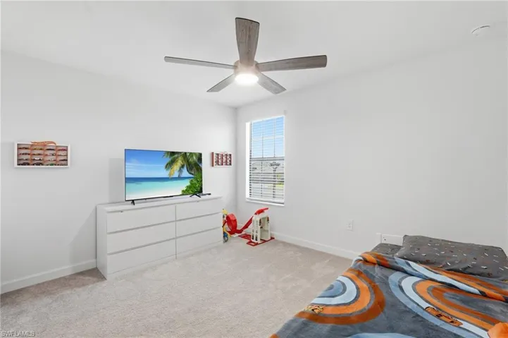Carpeted room featuring a window with horizontal blinds, a ceiling fan with integrated lighting, white baseboards, and light-toned walls